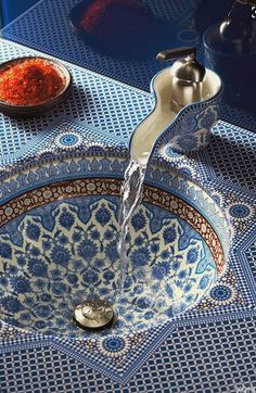 a faucet that is sitting on top of a blue and white bowl with red stuff in it