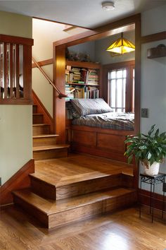 a bed sitting on top of a wooden floor next to a set of stairs