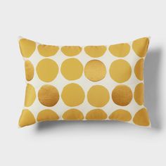 a yellow polka dot pillow on a white background