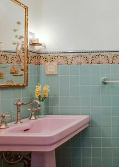 a pink sink and mirror in a small bathroom with blue tiles on the wall behind it