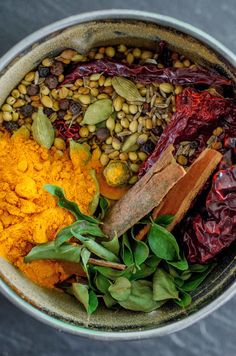 a bowl filled with lots of different types of food next to spices and seasonings