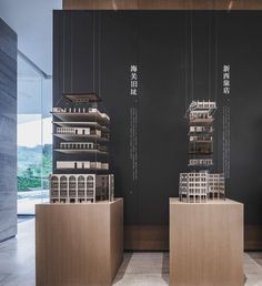 three model buildings on display in front of a black wall with chinese characters hanging from it