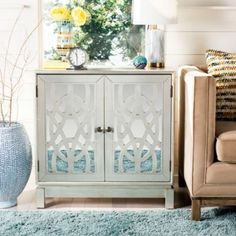 a white cabinet sitting next to a couch in a living room with blue rugs