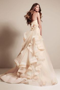 a woman in a wedding dress posing for the camera with her hair blowing back and shoulders down