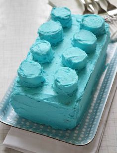 a cake with blue frosting on a plate next to a fork and spoons