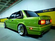 a green car parked in a parking garage next to a yellow wall with writing on it