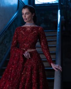 a woman in a red dress standing on stairs with her hand on her hip and looking off to the side