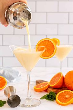 someone pouring orange juice into a martini glass