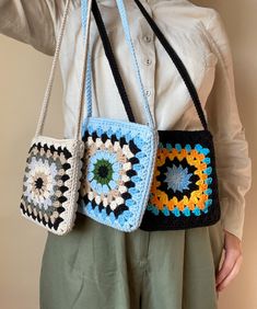 the woman is holding three crocheted purses in her hands and wearing a white shirt