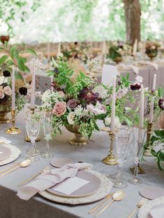 the table is set with flowers, candles and place settings for an elegant wedding reception