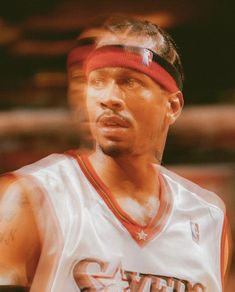 a basketball player with a red headband and tattoos on his face looking to the side