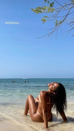 a woman laying on top of a sandy beach next to the ocean with her eyes closed