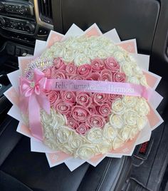 a bouquet of roses in the shape of a heart with a pink ribbon on it