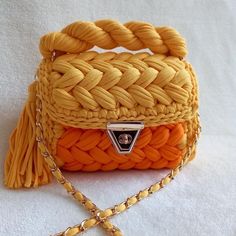 an orange and yellow handbag on a white surface with a chain attached to it