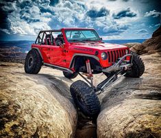 a red jeep is parked on some rocks