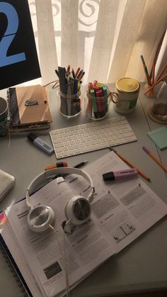 an open book sitting on top of a desk next to headphones