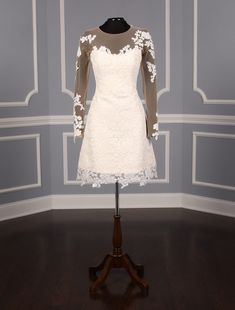 a white dress on display in a room with wood flooring and gray wall behind it