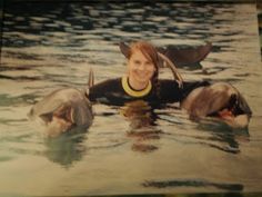 a woman is floating in the water with two dolphins