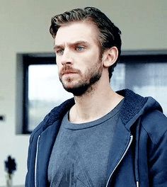 a man in a blue hoodie is looking at the camera with an intense look on his face