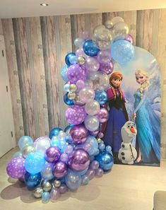 the balloon arch is made up of balloons and frozen princess characters are on display behind it