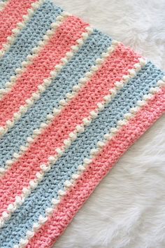 a crocheted blanket laying on top of a white furnishing covered floor