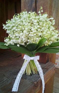 a bouquet of white flowers sitting on top of a wooden table