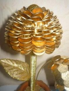 a gold flower sitting on top of a table next to some coins and a potted plant