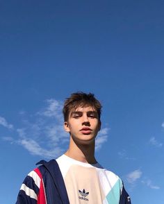 a young man standing in front of a blue sky