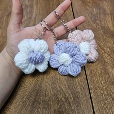 three crocheted flower keychains in the palm of someone's hand