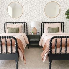 two twin beds in a bedroom with wallpaper and mirrors on the walls above them