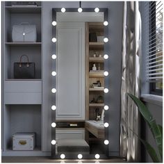 a large mirror with lights on it in a room next to a shelf and window