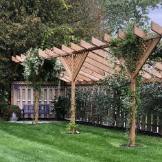 a wooden pergolan in the middle of a yard with green grass and trees