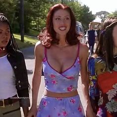 three young women are walking down the street with one holding her hand and smiling at the camera