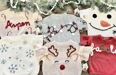 four sweaters with reindeer and snowman faces on them, all in different colors