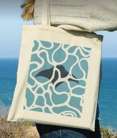 a person carrying a blue and white tote bag with a bird design on it
