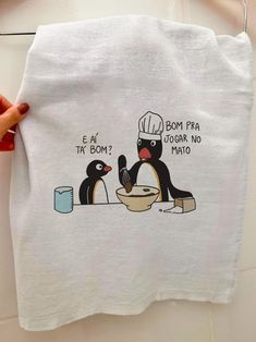 a person holding a white towel with penguins on it and one penguin is eating from a bowl