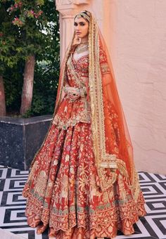 a woman in a red and gold bridal gown standing on a tiled floor next to a