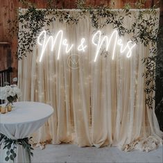 a white table topped with a vase filled with flowers next to a sign that says mr and mrs