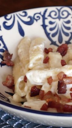 a bowl filled with pasta and bacon on top of a table