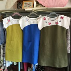 three different colored dresses hanging on a rack