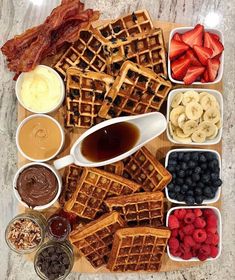 waffles, fruit, and other foods are arranged on a wooden platter