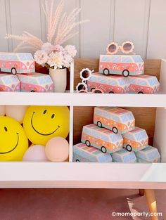 a shelf filled with boxes and balloons next to a potted plant on top of a table