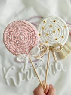 two crocheted lollipops are being held by someone's hand