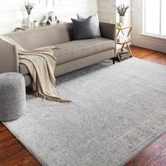 a living room area with a couch, chair and rug on the hardwood flooring