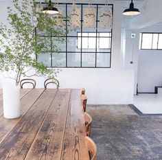 a wooden table and chairs in a large room with windows on the wall behind it