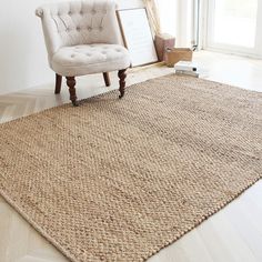 a white chair sitting on top of a wooden floor next to a large brown rug