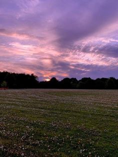 the sun is setting over an open field