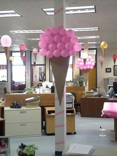 an ice cream cone decorated with pink and gold balloons in an office cubicle area