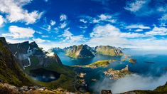 an aerial view of some mountains and the ocean with clouds in the sky over them