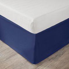 a blue and white bed spread on top of a wooden floor